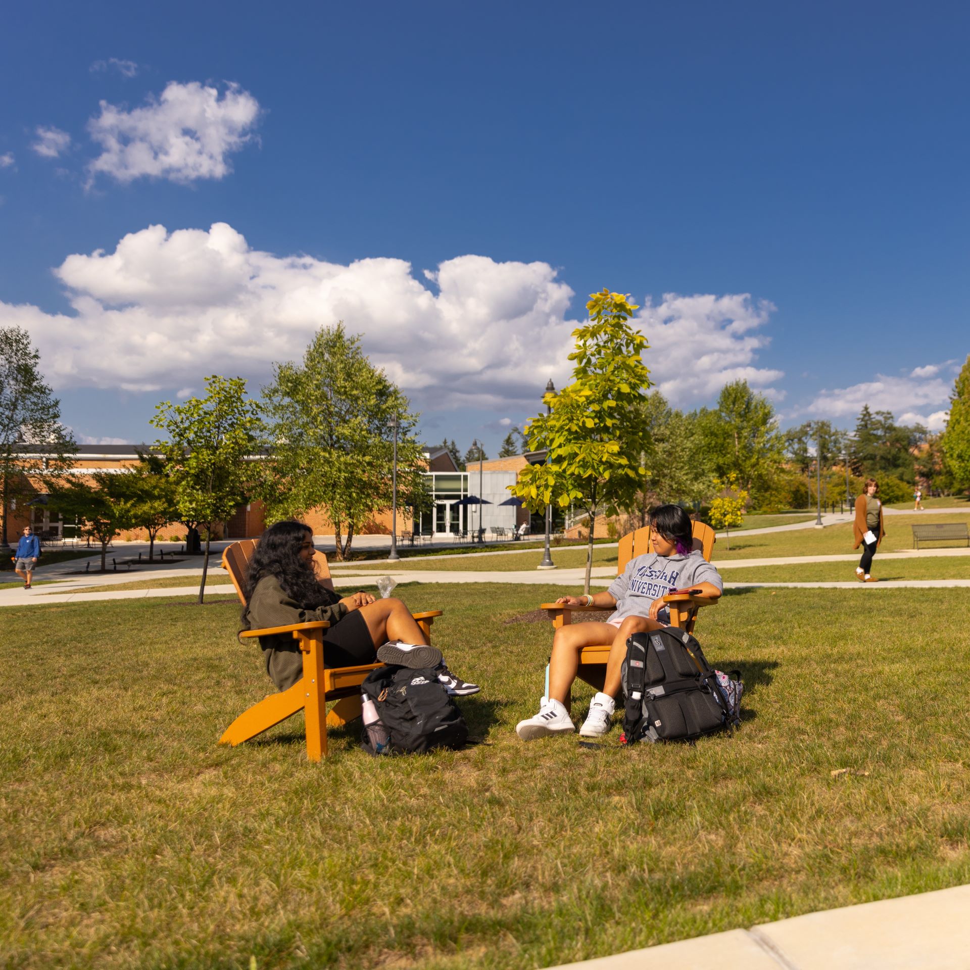 students sitting outside in adirondack chairs talking