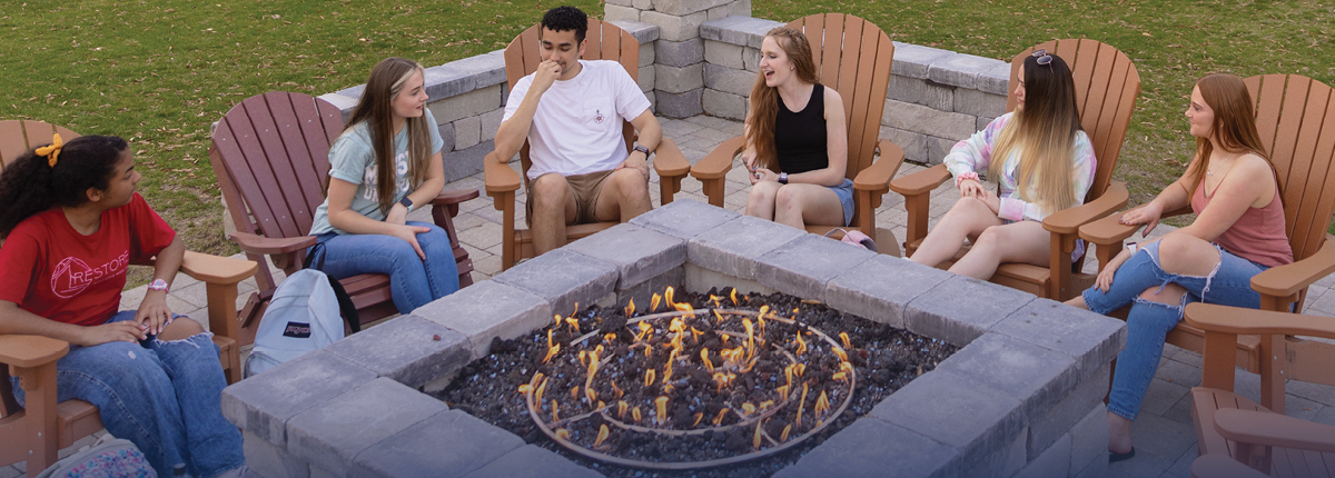 Students sitting around a firepit and chatting